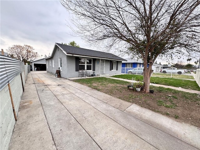 view of front of property with fence, a front yard, stucco siding, a garage, and an outbuilding