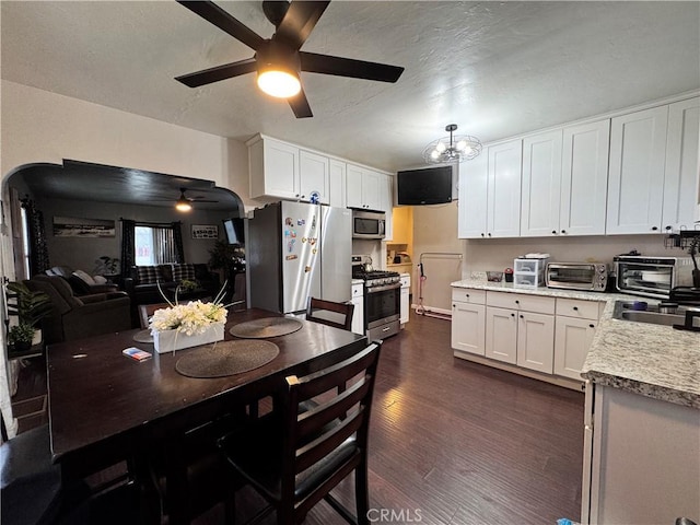 kitchen featuring light countertops, arched walkways, white cabinets, stainless steel appliances, and dark wood-style flooring