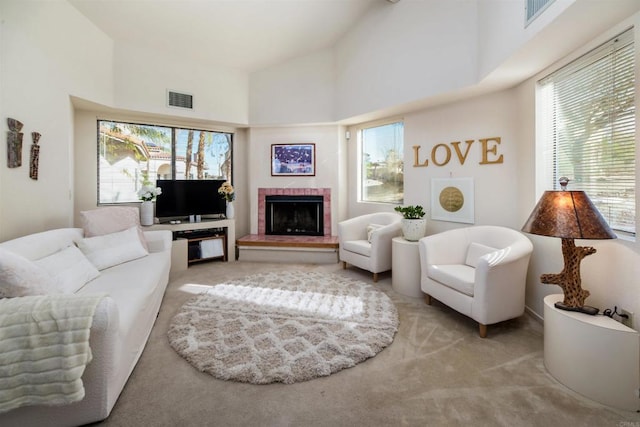 carpeted living area featuring high vaulted ceiling, a brick fireplace, and visible vents