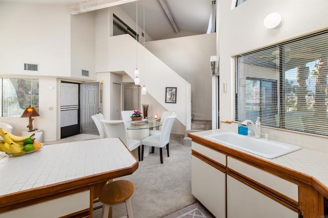 interior space with tile countertops, white cabinetry, visible vents, and a sink