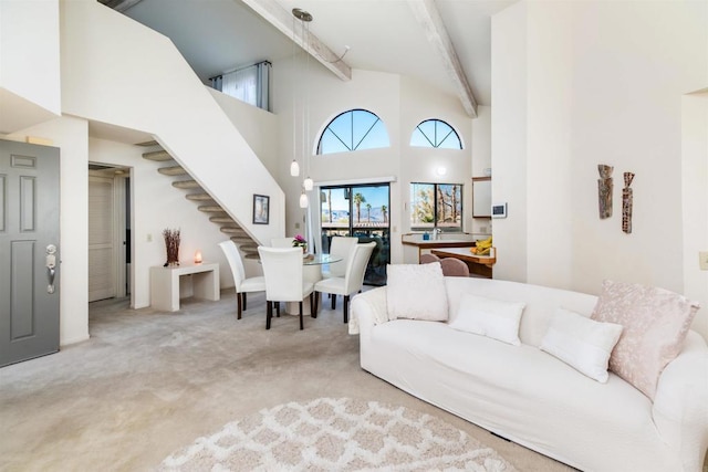 carpeted living area with high vaulted ceiling, stairway, and beam ceiling