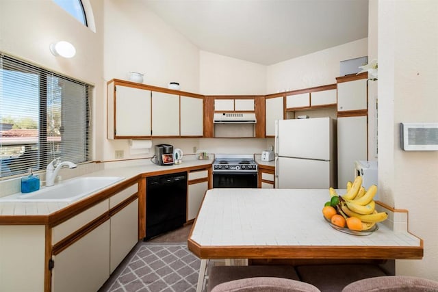 kitchen featuring lofted ceiling, under cabinet range hood, a sink, a healthy amount of sunlight, and black appliances