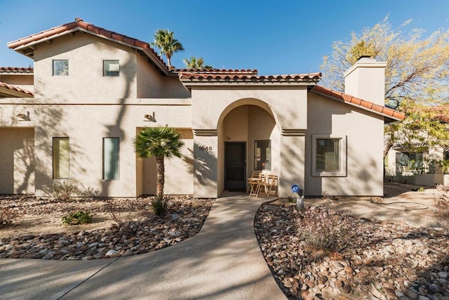 mediterranean / spanish-style home with a patio, a chimney, and stucco siding