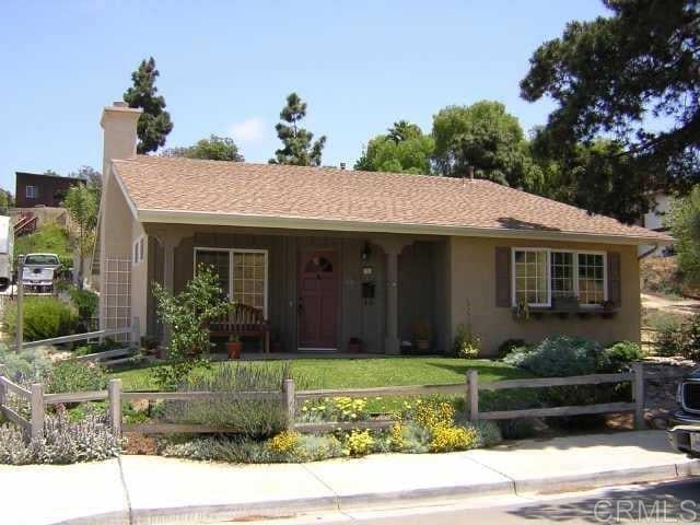 single story home with a fenced front yard, a chimney, stucco siding, a porch, and a shingled roof