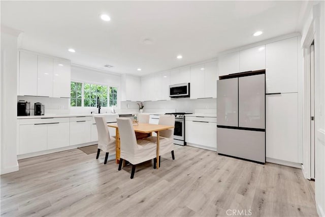 kitchen featuring light wood-style flooring, modern cabinets, freestanding refrigerator, stainless steel electric stove, and light countertops