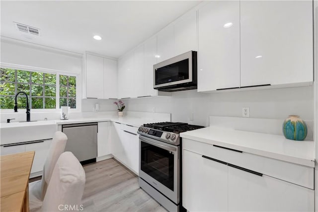 kitchen with stainless steel appliances, light countertops, visible vents, white cabinets, and modern cabinets