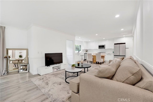 living area with recessed lighting, baseboards, crown molding, and light wood finished floors