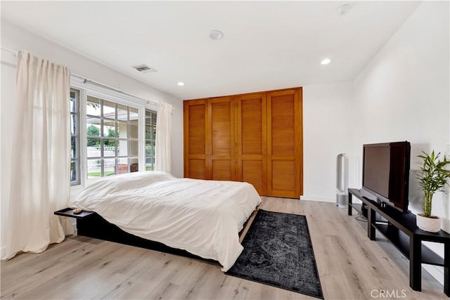 bedroom with light wood finished floors, visible vents, a closet, and recessed lighting