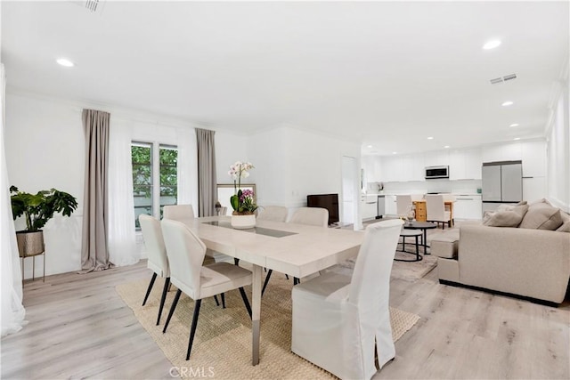 dining area with light wood-type flooring, visible vents, and recessed lighting