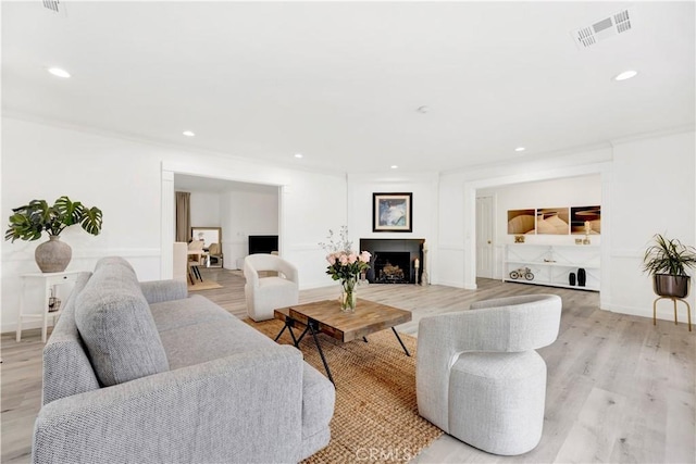 living room with light wood finished floors, baseboards, visible vents, a fireplace, and recessed lighting