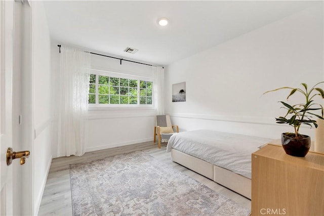 bedroom with wood finished floors, visible vents, and baseboards