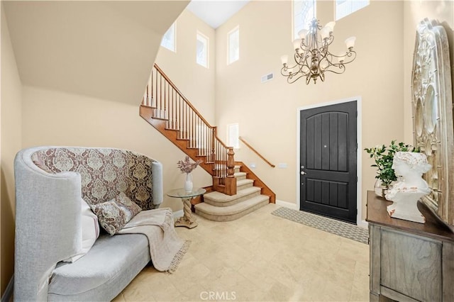 entrance foyer with visible vents, baseboards, stairs, a high ceiling, and a notable chandelier