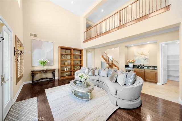 living room featuring stairway, wood finished floors, visible vents, and baseboards