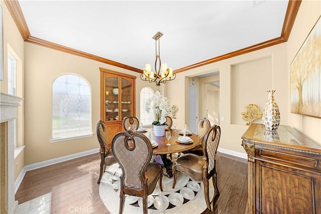 dining room featuring dark wood finished floors, crown molding, a notable chandelier, and baseboards