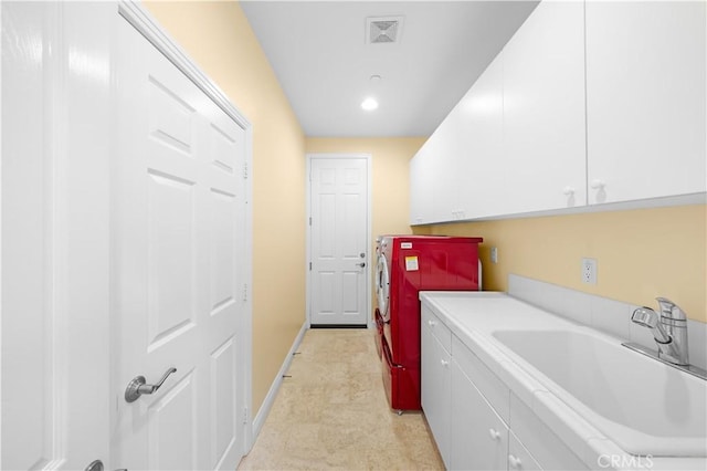 clothes washing area with baseboards, visible vents, separate washer and dryer, cabinet space, and a sink