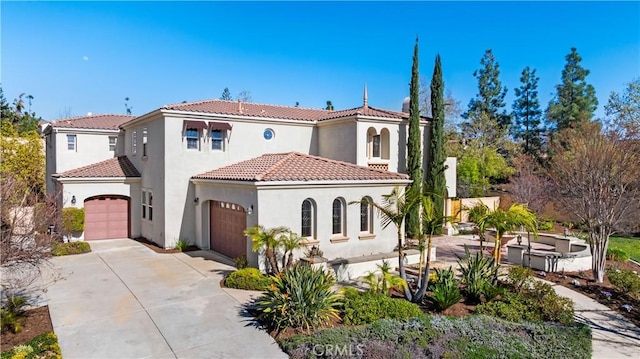 mediterranean / spanish-style house with concrete driveway, a tiled roof, a garage, and stucco siding