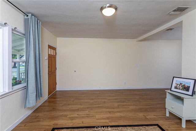 unfurnished room featuring visible vents, baseboards, and wood finished floors