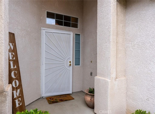 doorway to property featuring stucco siding