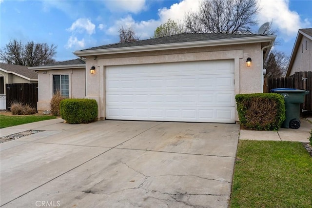 garage featuring fence and concrete driveway