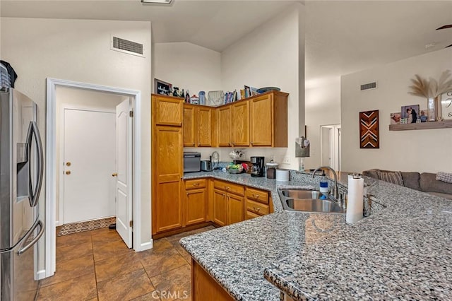 kitchen featuring light stone counters, a peninsula, a sink, visible vents, and stainless steel fridge with ice dispenser