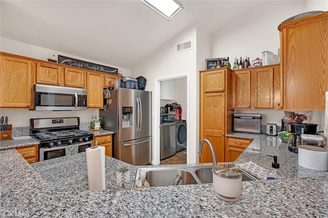 kitchen with stainless steel appliances, visible vents, vaulted ceiling, and light stone countertops