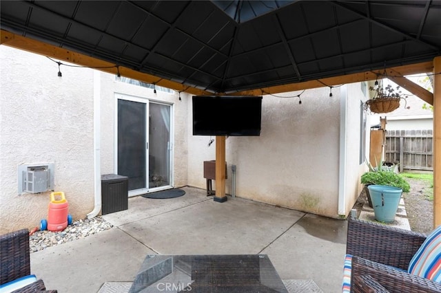 view of patio with a wall mounted air conditioner, fence, and a gazebo