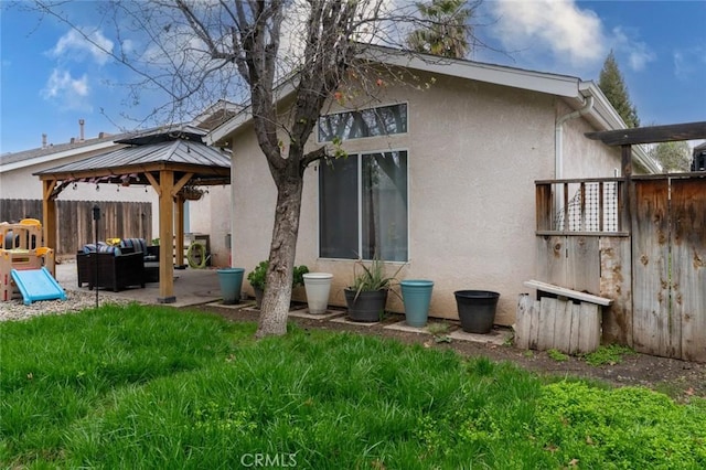 back of property featuring a patio, an outdoor hangout area, fence, a gazebo, and stucco siding