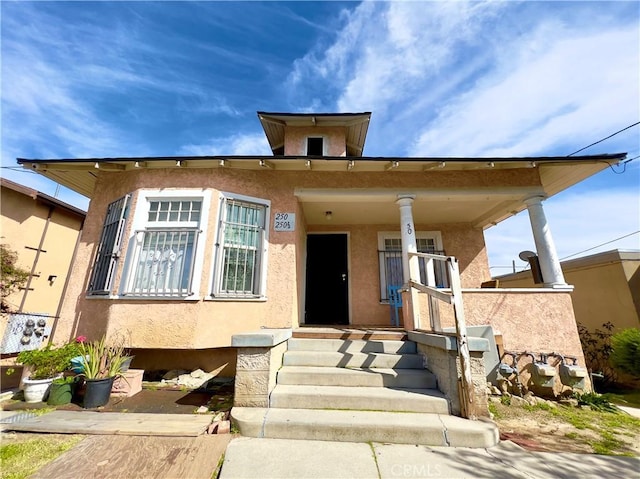 bungalow-style home with covered porch and stucco siding