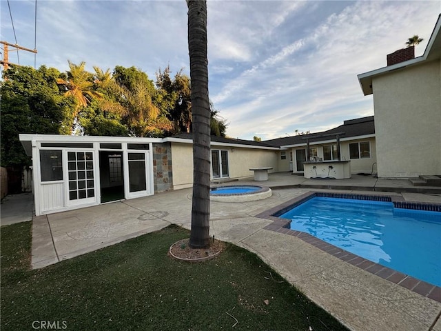 pool with area for grilling, a patio, and an in ground hot tub