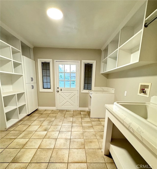 washroom featuring light tile patterned floors, laundry area, washer hookup, a sink, and baseboards