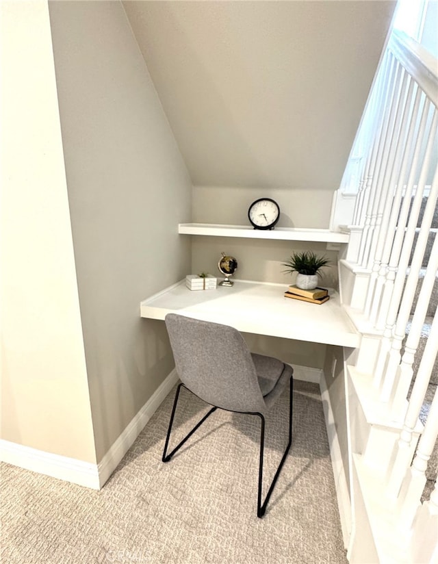 office space with carpet, vaulted ceiling, built in desk, and baseboards