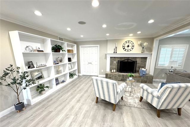 living area with ornamental molding, a stone fireplace, and light wood-style flooring