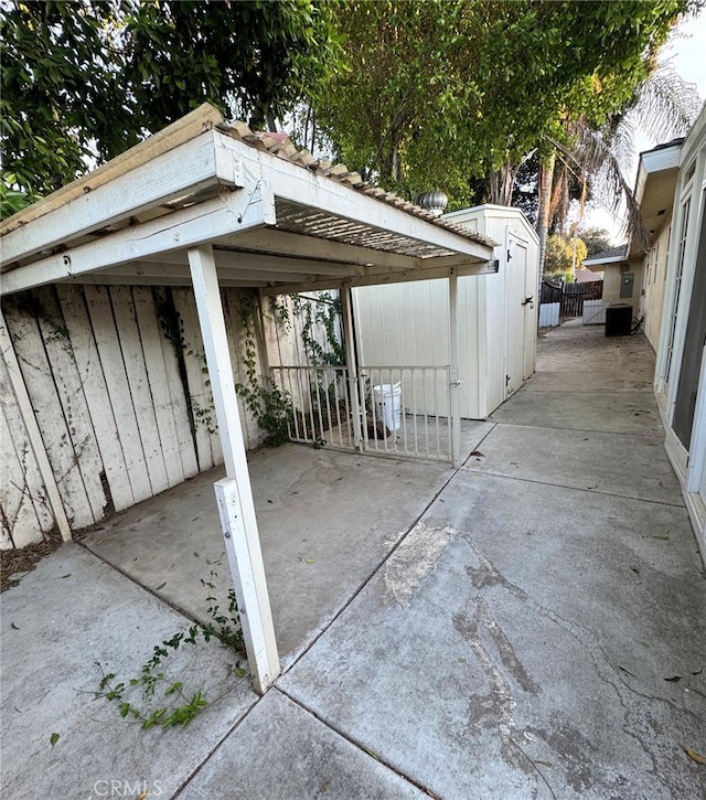 view of patio / terrace featuring a storage unit, fence, and an outdoor structure