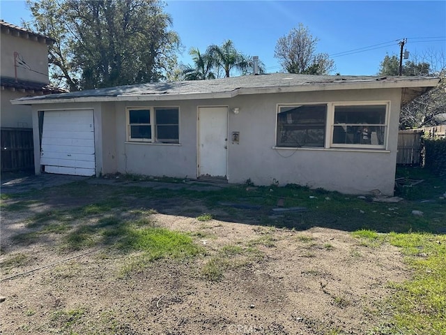 view of front of home with an attached garage, fence, and stucco siding