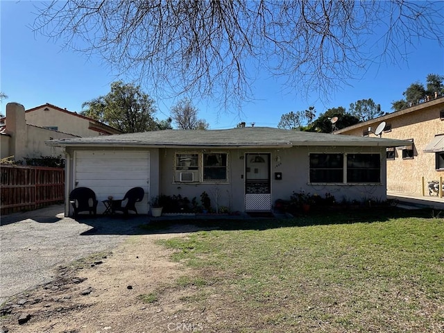 ranch-style house with an attached garage, fence, dirt driveway, stucco siding, and a front yard