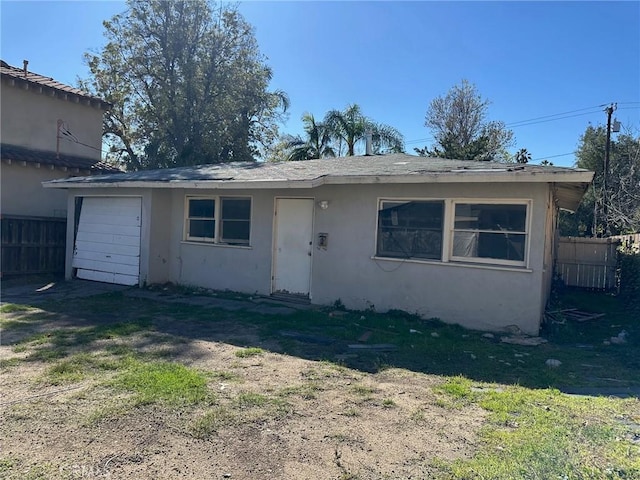 view of front of property featuring an attached garage, fence, and stucco siding