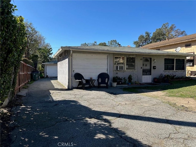 view of front of home featuring a garage, an outbuilding, fence, and stucco siding