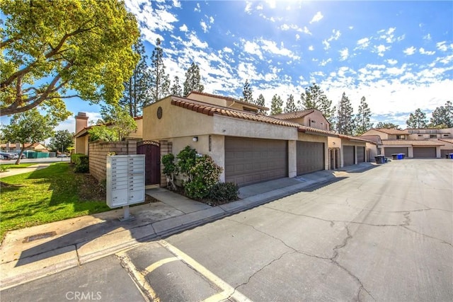 view of side of home featuring a tiled roof, mail area, and stucco siding