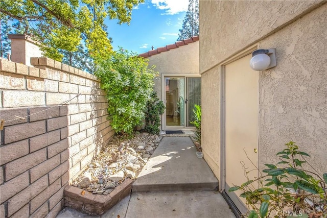 view of side of property with a tile roof, fence, and stucco siding