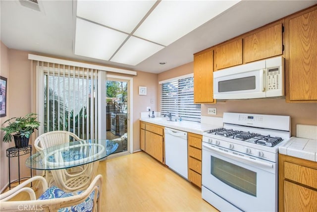 kitchen featuring white appliances, visible vents, tile counters, brown cabinets, and light wood-type flooring