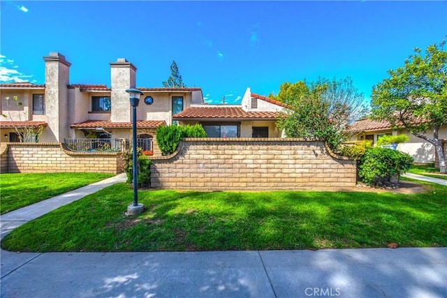 view of front of home with a chimney, fence, a front lawn, and a tiled roof