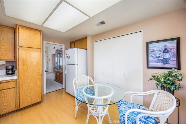 kitchen featuring light wood-style floors, freestanding refrigerator, visible vents, and tile counters