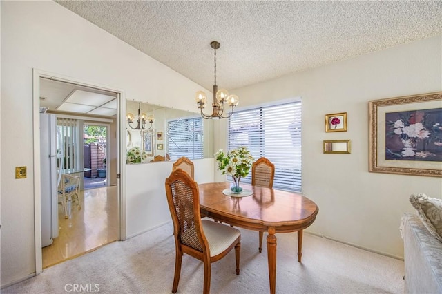 dining room featuring lofted ceiling, a textured ceiling, light colored carpet, and an inviting chandelier