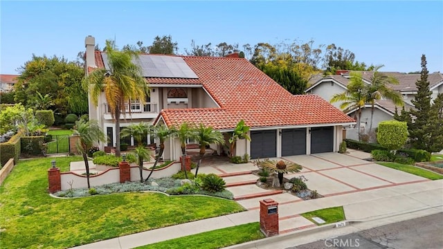 mediterranean / spanish-style home with a tiled roof, a front lawn, an attached garage, and roof mounted solar panels