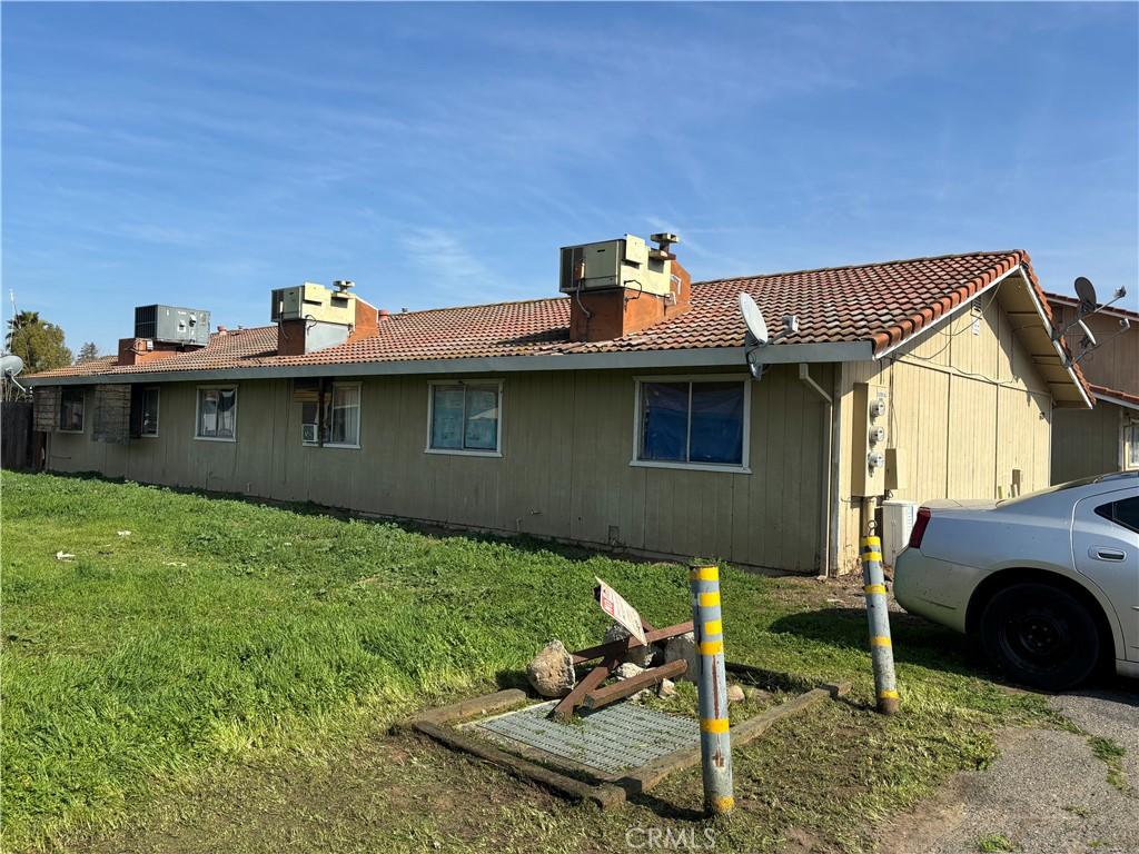 view of side of property featuring a lawn, a tile roof, and central air condition unit