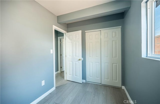 unfurnished bedroom featuring baseboards, a closet, and wood finished floors