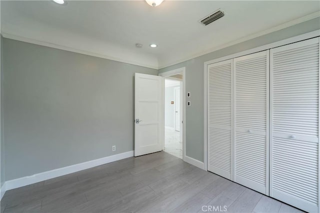 unfurnished bedroom with a closet, light wood-type flooring, baseboards, visible vents, and recessed lighting