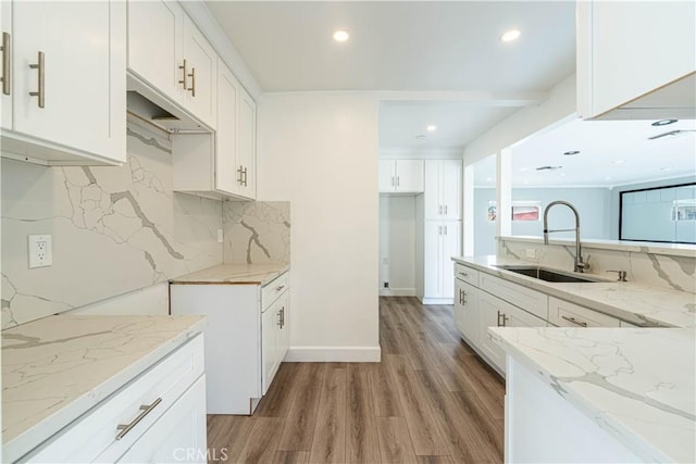 kitchen with decorative backsplash, light wood-style flooring, recessed lighting, a sink, and light stone counters