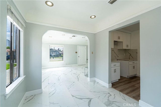 hall with marble finish floor, arched walkways, baseboards, and visible vents