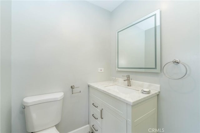 bathroom with baseboards, toilet, and vanity